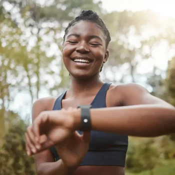 African runner woman, smart watch and park for check, smile or happy for time, results or fitness in nature. Girl, iot clock and monitor for speed, heart rate or smile for exercise, workout or health